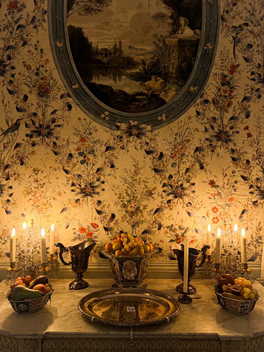 Candlelit dining wall in a hand-painted chinoiserie floral wallpaper with silver candelabra