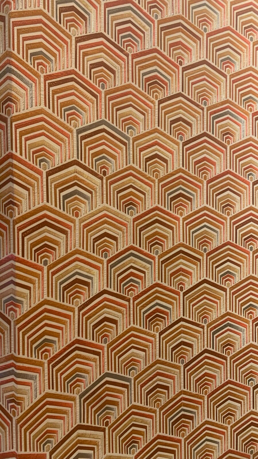 Close-up of a warm rust-toned hexagonal geometric wallpaper texture